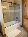 The shared upstairs bath has a combination tub/shower with glass doors.